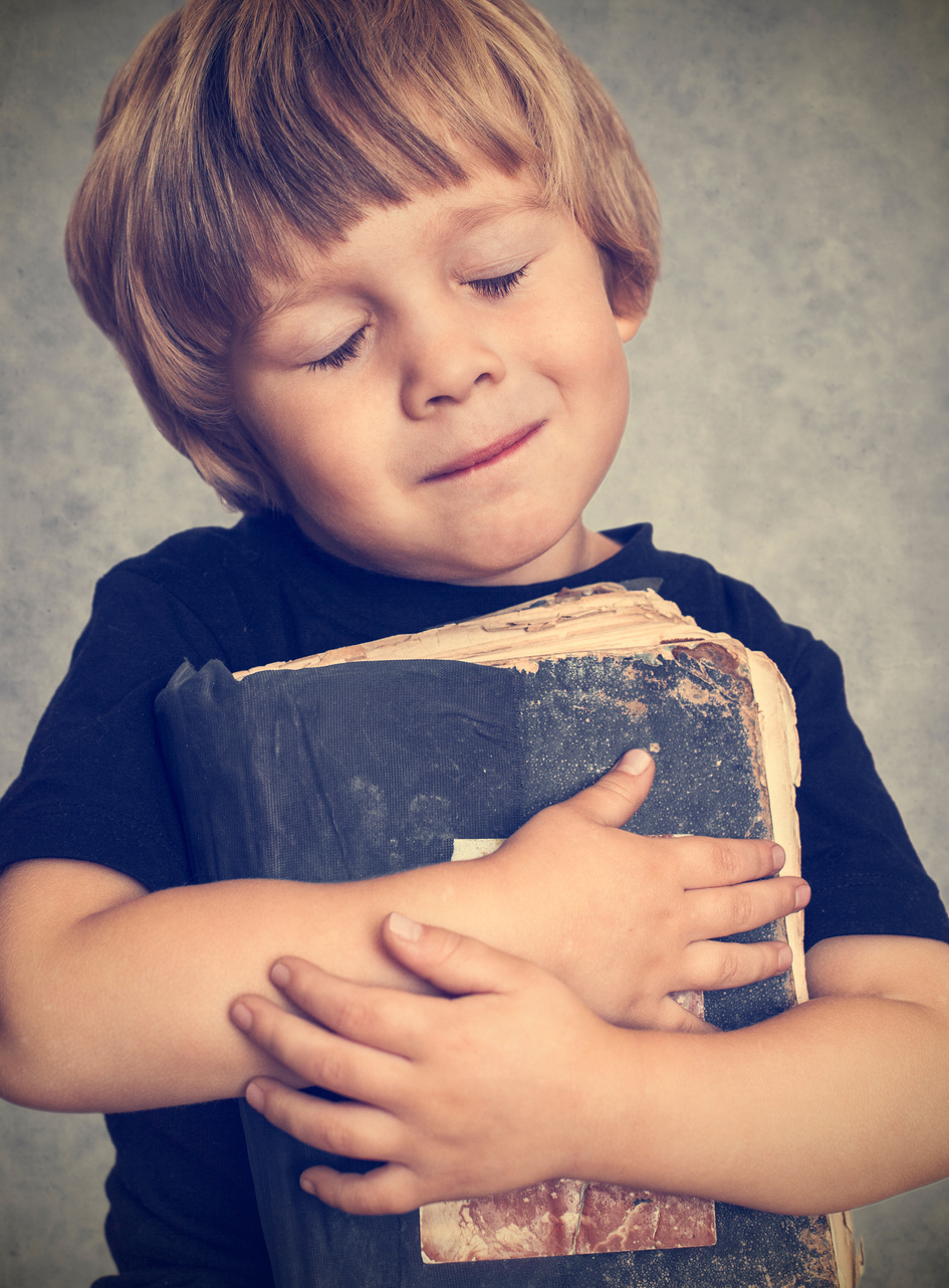 Little boy hugging an old book